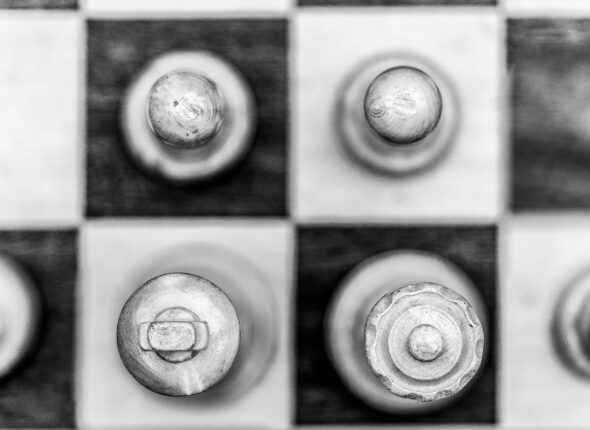Grayscale aerial shot of chess pieces on a chessboard