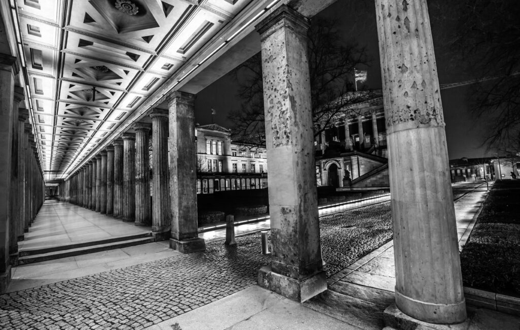 Grayscale shot of a hallway with pillars